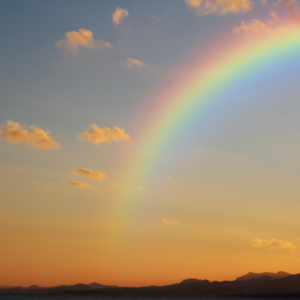 Tramonto dorato con un arcobaleno luminoso che attraversa il cielo, simbolo di speranza e trasformazione. Liberati dalla paura e trova la serenità interiore