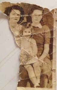 Foto d'epoca strappata e usurata raffigurante tre persone, due donne e una bambina, simbolo di memoria e passato, collegata all'Intelligenza Artificiale Memoria.